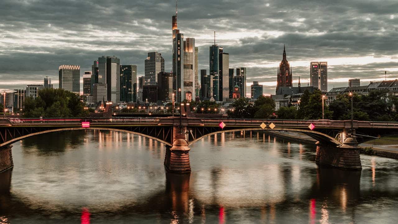 Der Blick auf Frankfurt präsentiert sich mit einer markanten Brücke im Vordergrund und der beeindruckenden Skyline der Stadt.