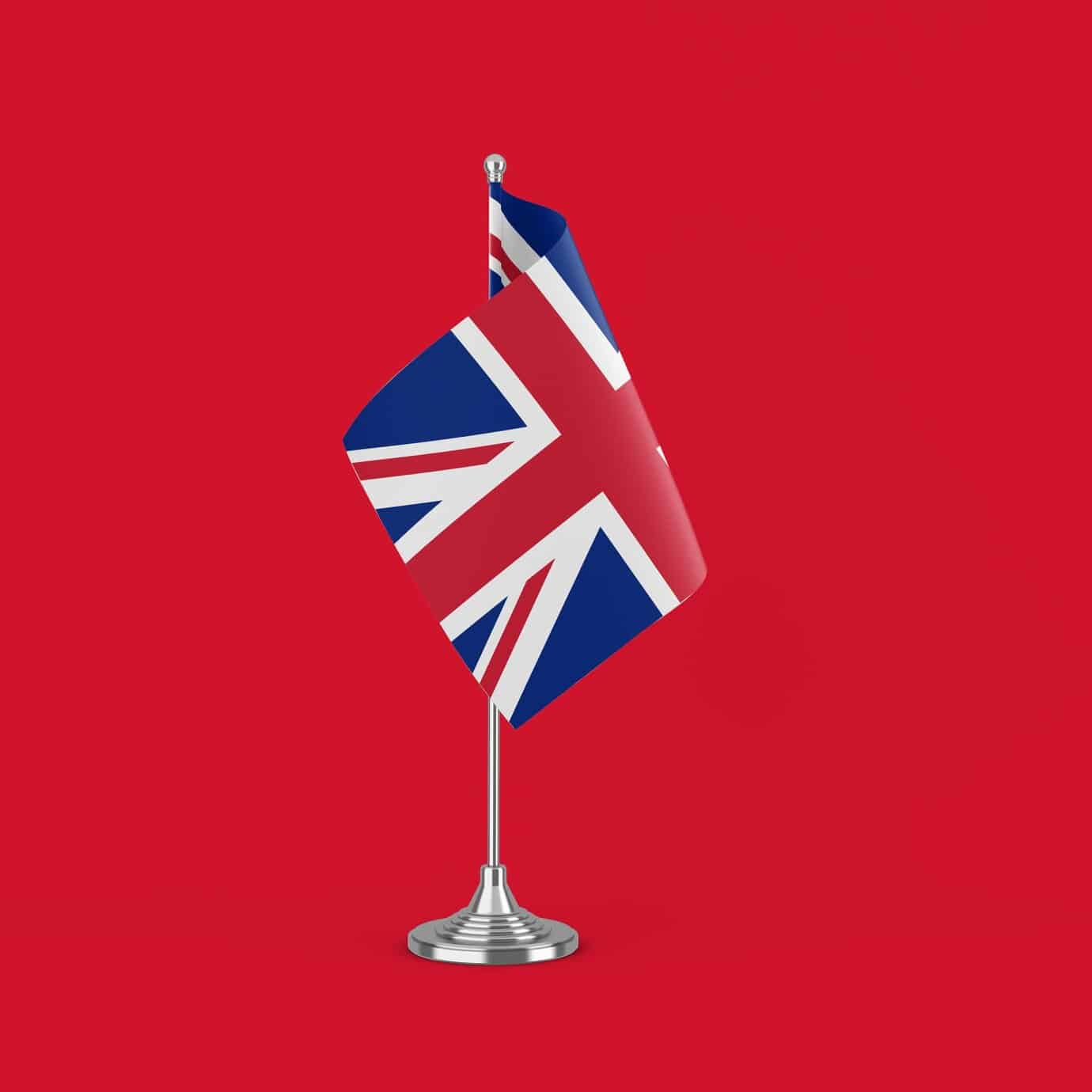 Kleine Tischflagge des Großbritanniens mit Union Jack-Design, auf einem silbernen Ständer montiert.